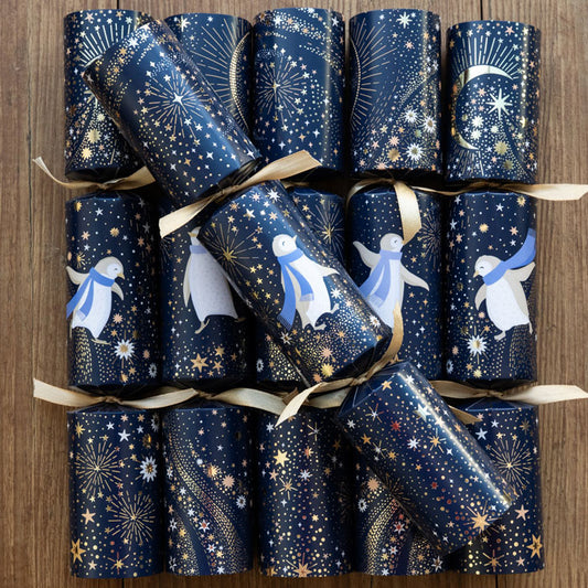 Set of six navy Christmas crackers with dancing penguins wearing blue scarves, surrounded by gold stars and crescent moon.