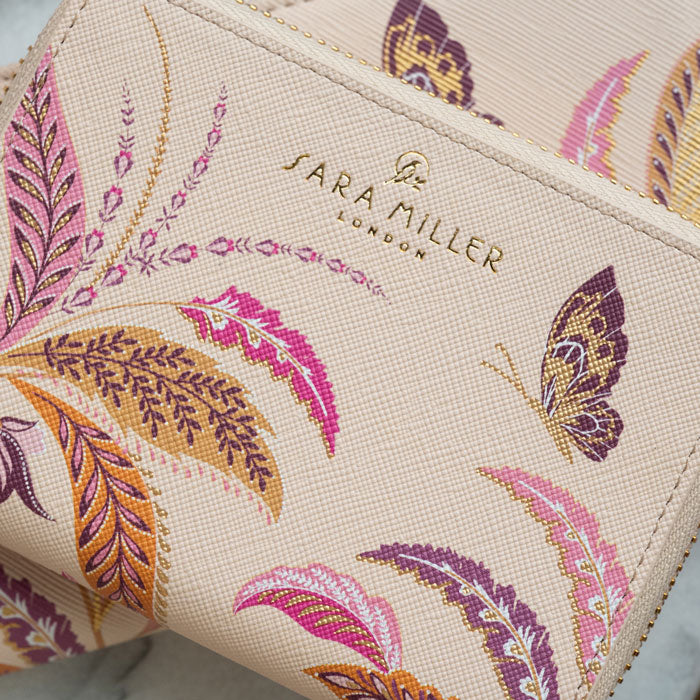 Close up of floral design on purse, can see gold embossed Sara Miller London logo and purse texture.
