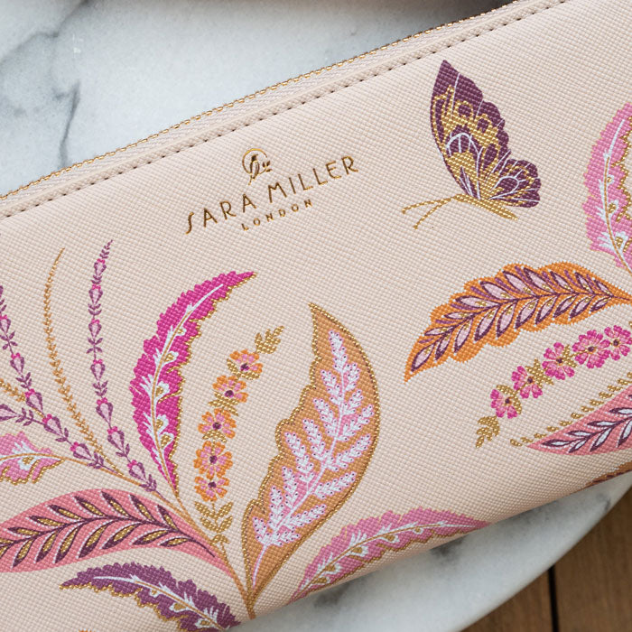 Close up of design on purse, can see texture of purse and embossed gold Sara Miller London logo.