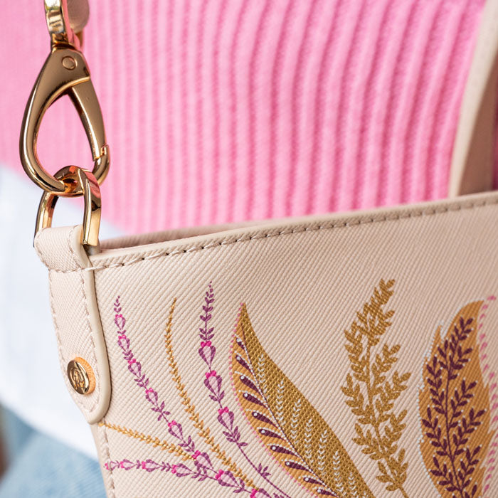 Close of of gold clip which attaches strap to the bag.