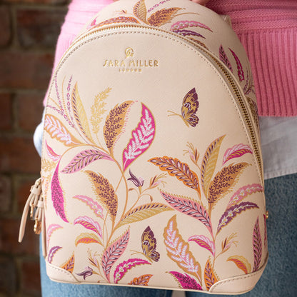 Cream mini backpack with floral design, someone holding close up.