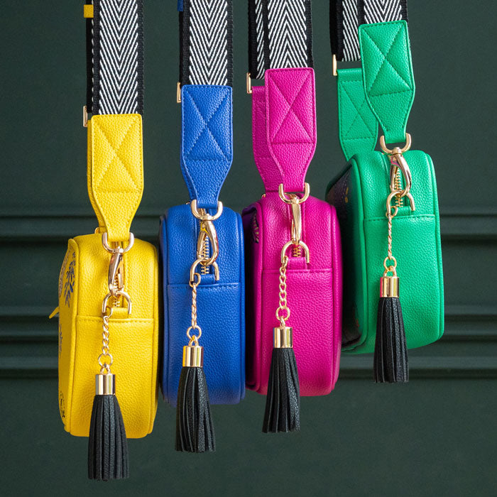 Yellow handbag next to others from the collection, in blue, pink and green.