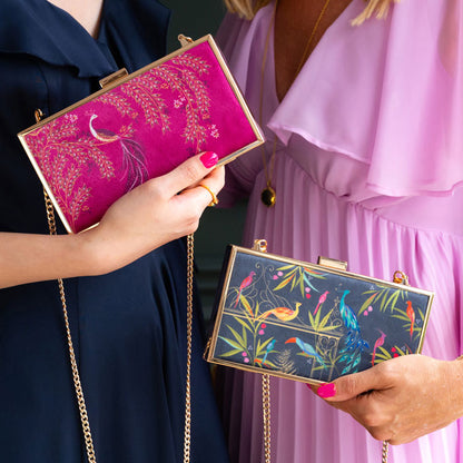 Two women holding colourful handbags with intricate designs.