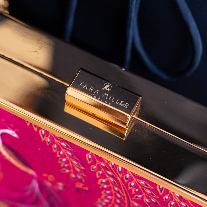 Close-up of a handbag with 'Sara Miller London' logo on a dark background