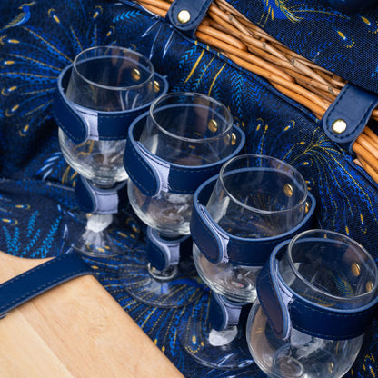 Set of four clear glasses with blue holders in a decorative blue picnic basket.
