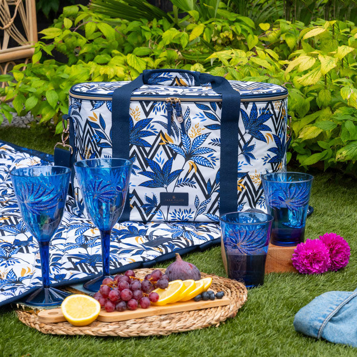 Blue and white floral-patterned cooler bag with picnic items on grass