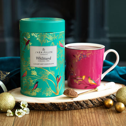 Hot chocolate tin in Green Birds print and Pink Birds mug on a wooden surface.