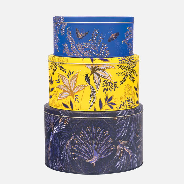 Stack of three cake tins in different colours, cobalt, yellow and indigo, each with floral and bird designs.