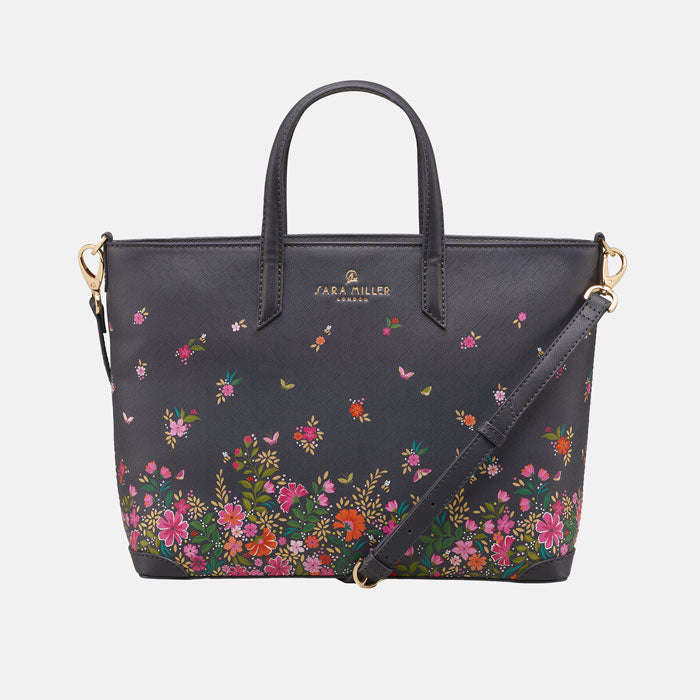 Ditsy floral medium tote bag with delicate floral design, shows cross body strap. White background.