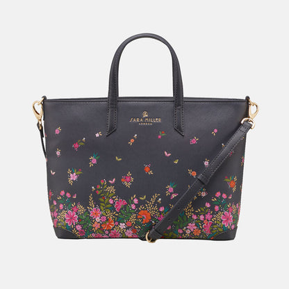 Ditsy floral medium tote bag with delicate floral design, shows cross body strap. White background.