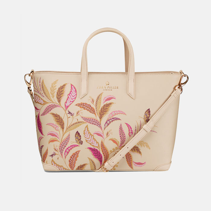 Cream tote style bag with floral design, shows crossbody strap which can be attached.