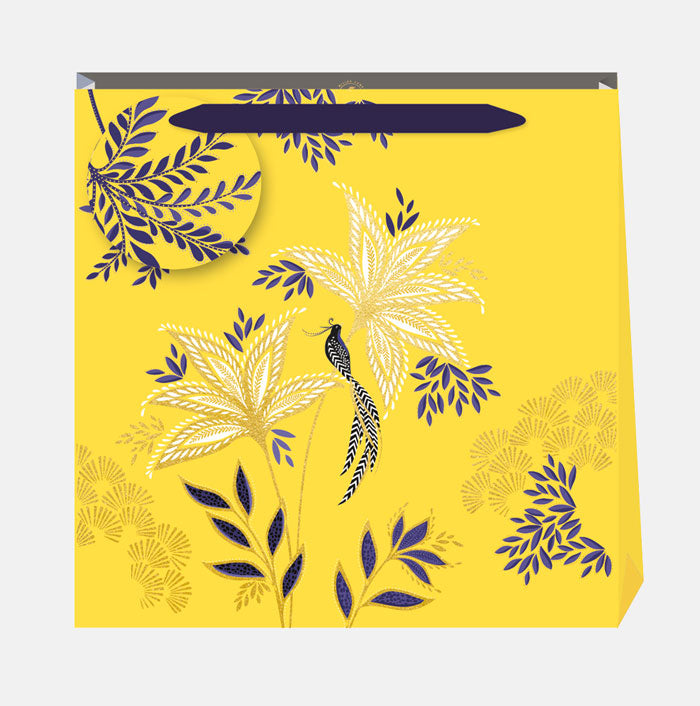 Warm yellow gift bag in botanic blooms design, with matching gift tag and indigo ribbon handles.
