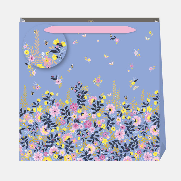 Floral-patterned gift bag with a blue background and pink ribbon handle, and matching gift tag.