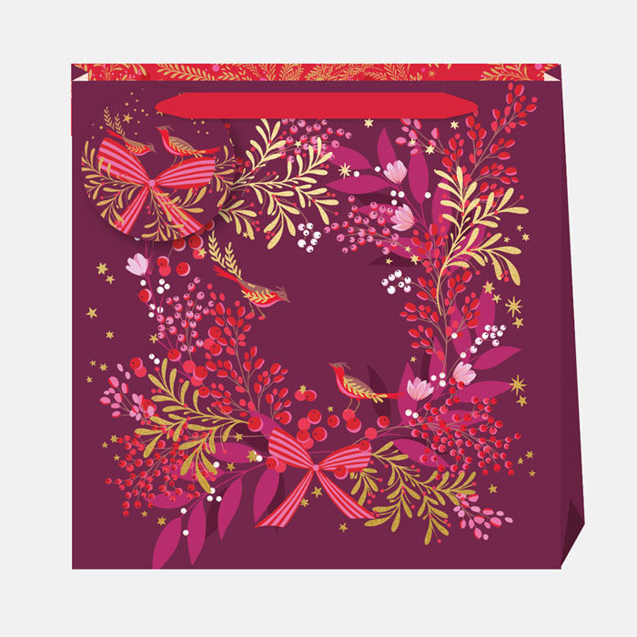 A plum Christmas gift bag with festive wreath, berries and robins.