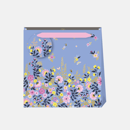 Floral-patterned gift bag with a blue background and pink ribbon handle, and matching gift tag.