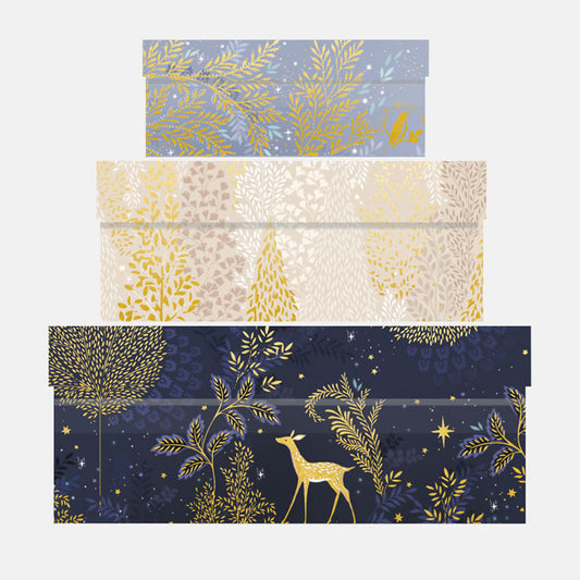 Set of three decorative gift boxes with gold leaf and deer designs on a blue, beige, and navy background.