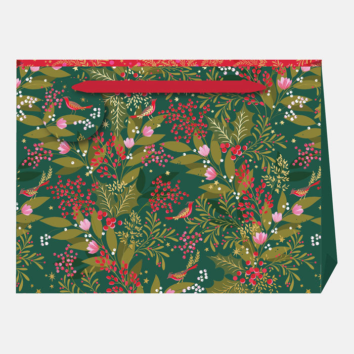 A Christmas gift bag with green, red and pink winter foliage, berries and robins on a green base, with matching gift tag and ribbon handles.