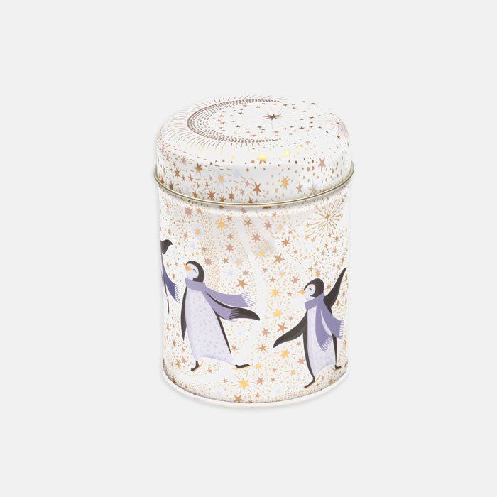 A cylindrical metal tin with a lid, decorated with penguin illustrations and gold starburst patterns on a white background.