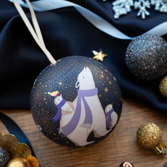 A round Christmas ornament featuring a polar bear and penguins wearing purple scarves, against a starry sky with gold embellishment.