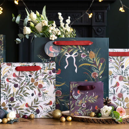 A collection of gift bags all with fig & fern festive designs, in shades of green, red and cream. A playful twist on traditional Christmas gift wrapping.