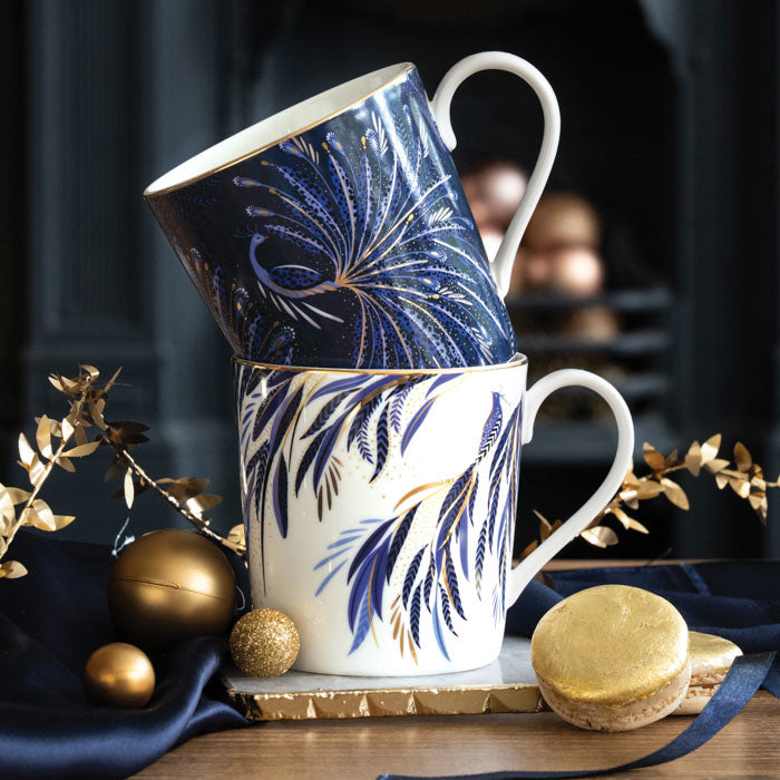 Two mugs stacked on a marble coaster, one is white and one is indigo both with gold embellishment.