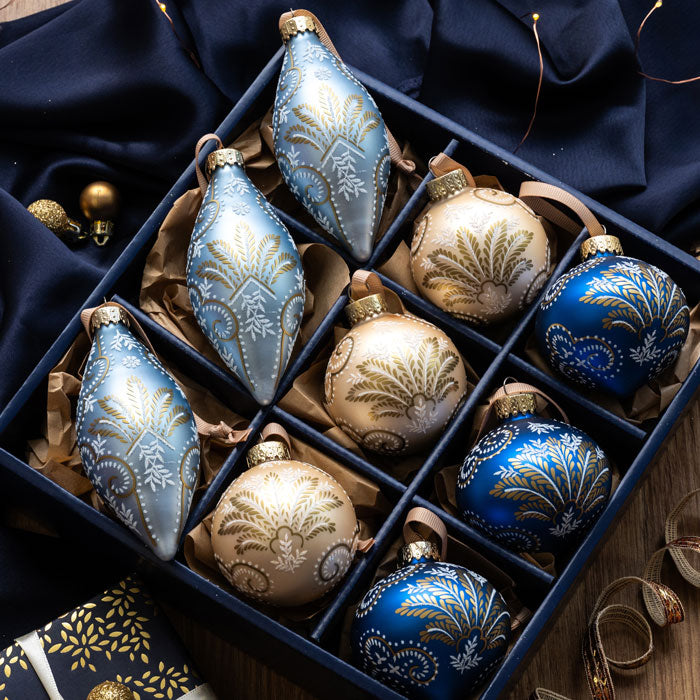 Decorative Christmas ornaments in a box with blue and gold colors.