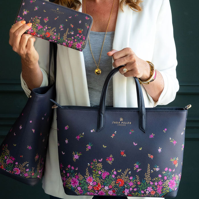 Model holding ditsy floral medium tote bag, along with matching large purse and large tote on other arm.