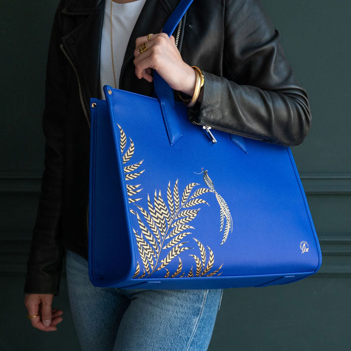 Blue boxy tote with botanic design, model wearing with moody colours background.