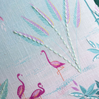 Close-up of fabric with flamingo and palm design on a light blue background