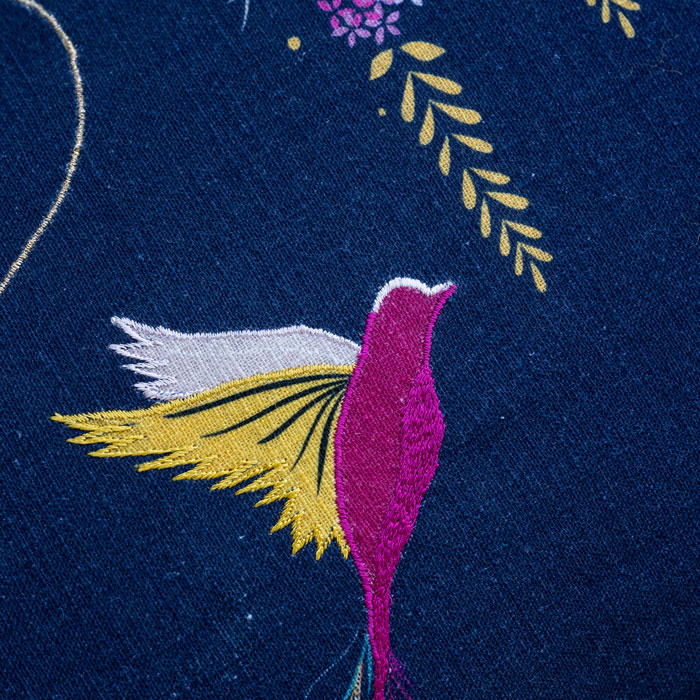 Close up of hummingbird design with embroidery and linen texture.