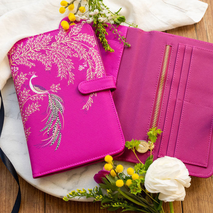 Fuchsia travel wallet with elegant bird design and gold detailing. Press stud closure. Shows inside compartments.