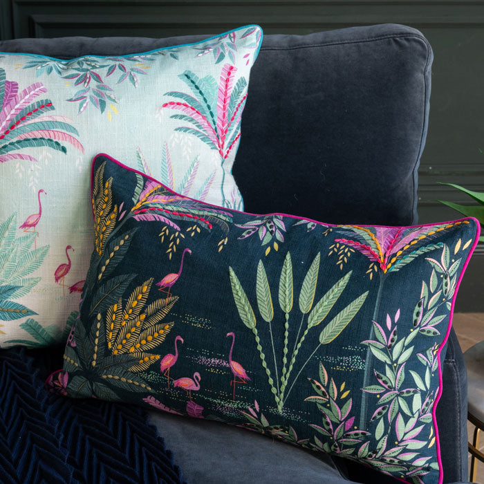 Decorative pillows with floral and flamingo patterns on a dark sofa.