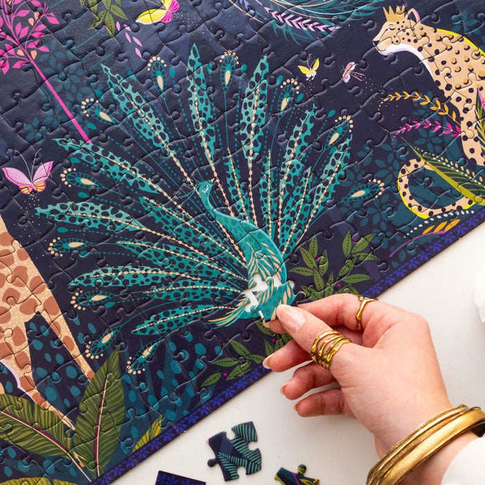 Colourful jungle themed puzzle with animals and foliage being completed, shows hand.