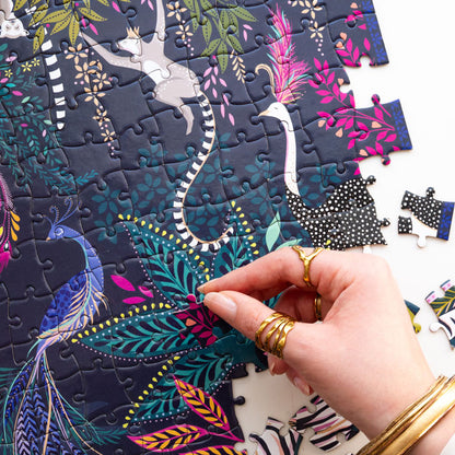 Colourful jungle themed puzzle with animals and foliage being completed, shows hand.