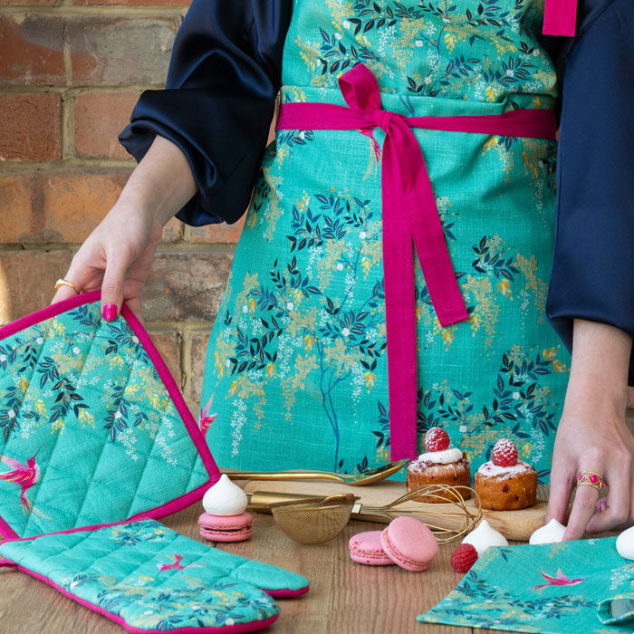 Person wearing a green apron hummingbird and foliage design.