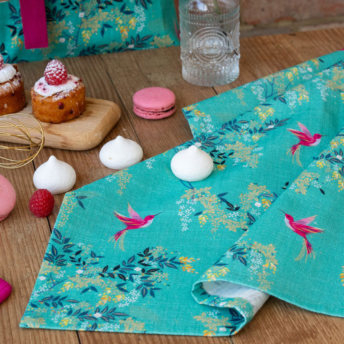 Green tea towel with hummingbird and foliage design.