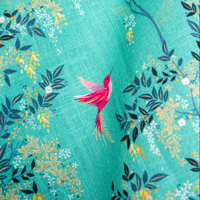 Close up of green tea towel with hummingbird and foliage design.