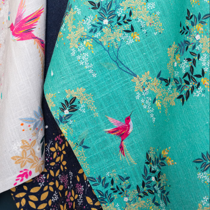 Close up of green tea towel with hummingbird and foliage design.