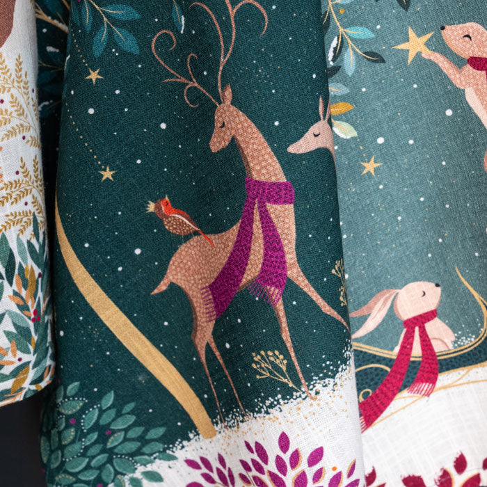Festive tea towel with reindeer and rabbit designs on a dark green background