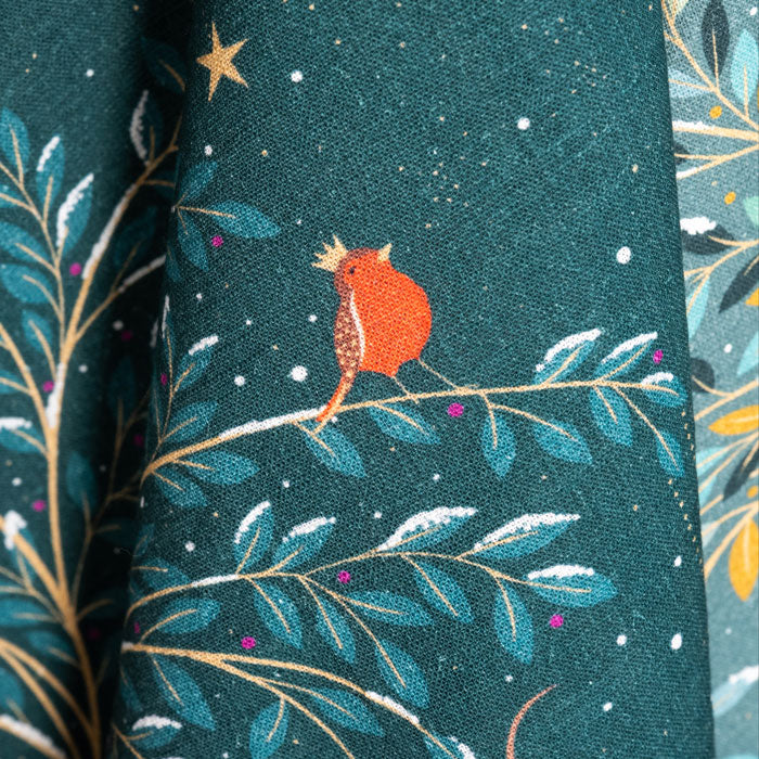 Tea towel with a decorative pattern of a robin on a branch, stars, and leaves on a dark green background.