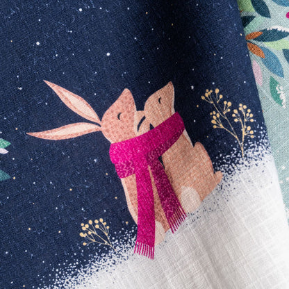 Festive tea towel with rabbits in a moonlit scene.