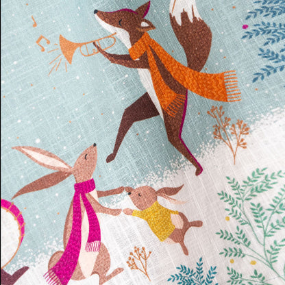 Tea towel with festive design featuring animals playing musical instruments on a snowy background.