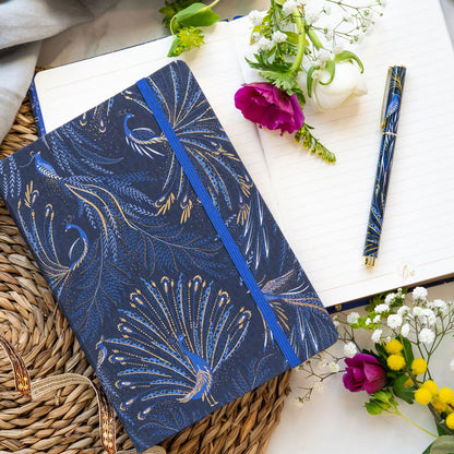 Notebook with peacock feather design on an indigo background with gold detailing, matching pen.