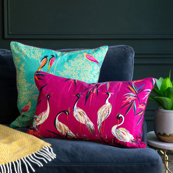 Pink cushion with heron design on the sofa, with the green birds cushion behind.