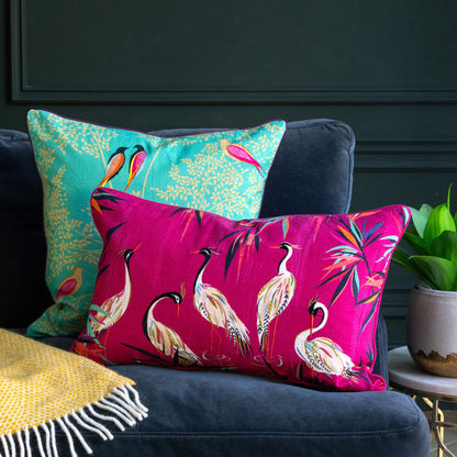 Pink cushion with heron design on the sofa, with the green birds cushion behind.