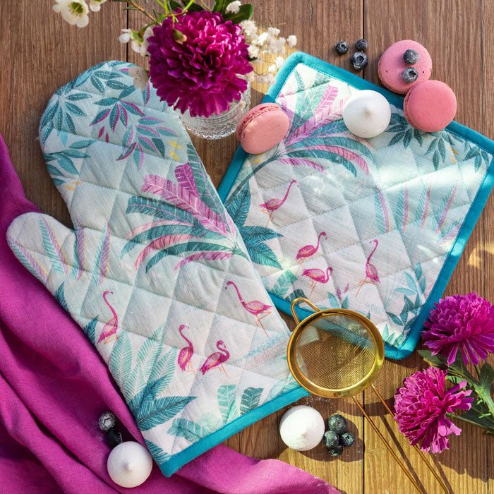 Flamingo and palm design oven mitt and pot holder on a wooden surface.