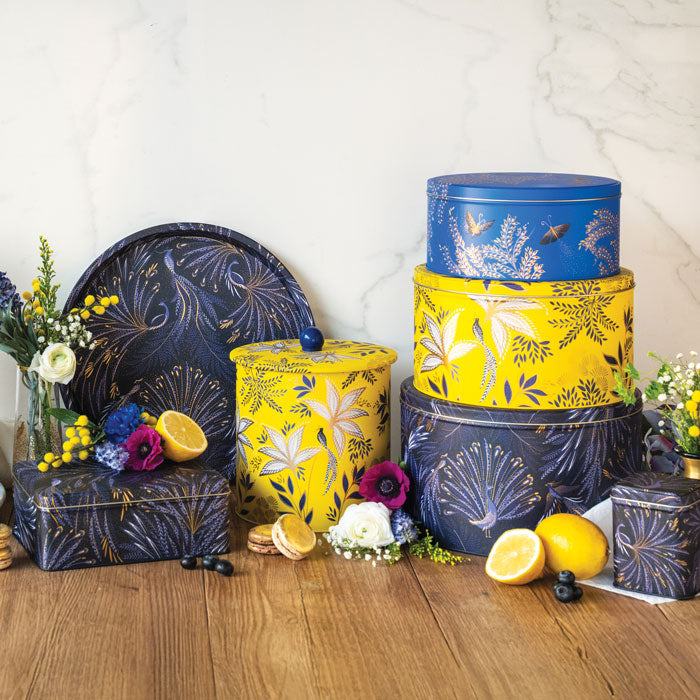 Storage tins in different colours and shapes, cobalt, yellow and indigo, each with floral and bird designs.