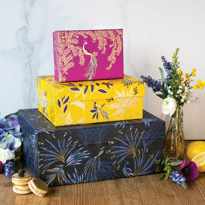 Three stacked gift boxes in different colours, fuchsia, yellow and indigo, in different floral and bird designs.