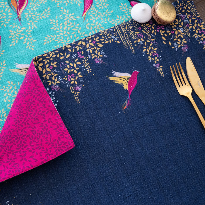 Navy rectangular placemat with hummingbird design and gold cutlery.