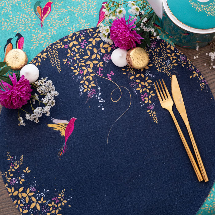 Navy round placemat with hummingbird design and foliage.
